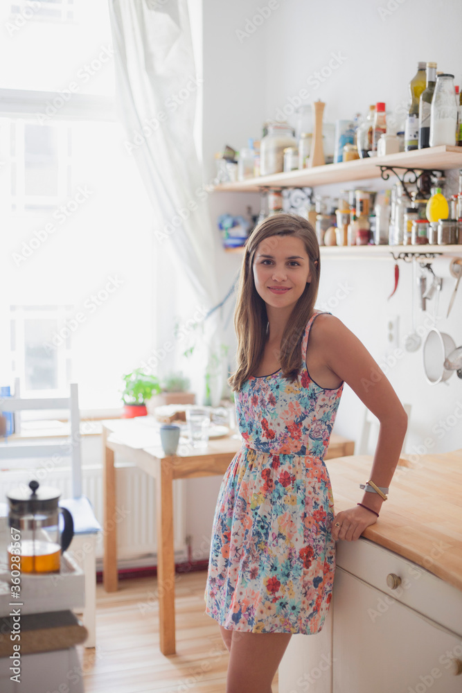 Portrait of beautiful woman standing by counter in kitchen at home