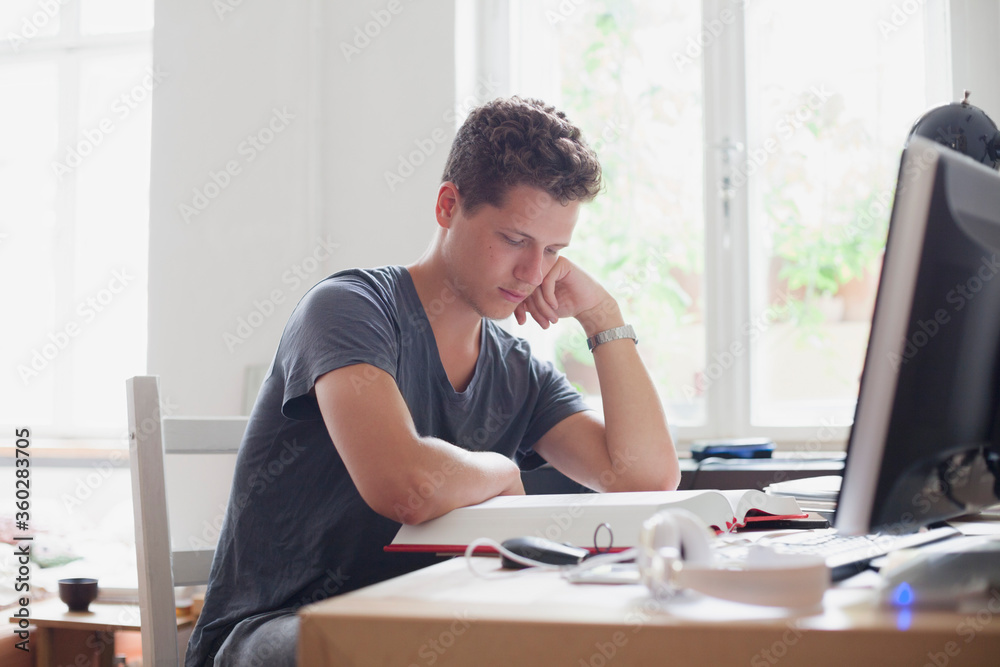 Young handsome university student studying at home