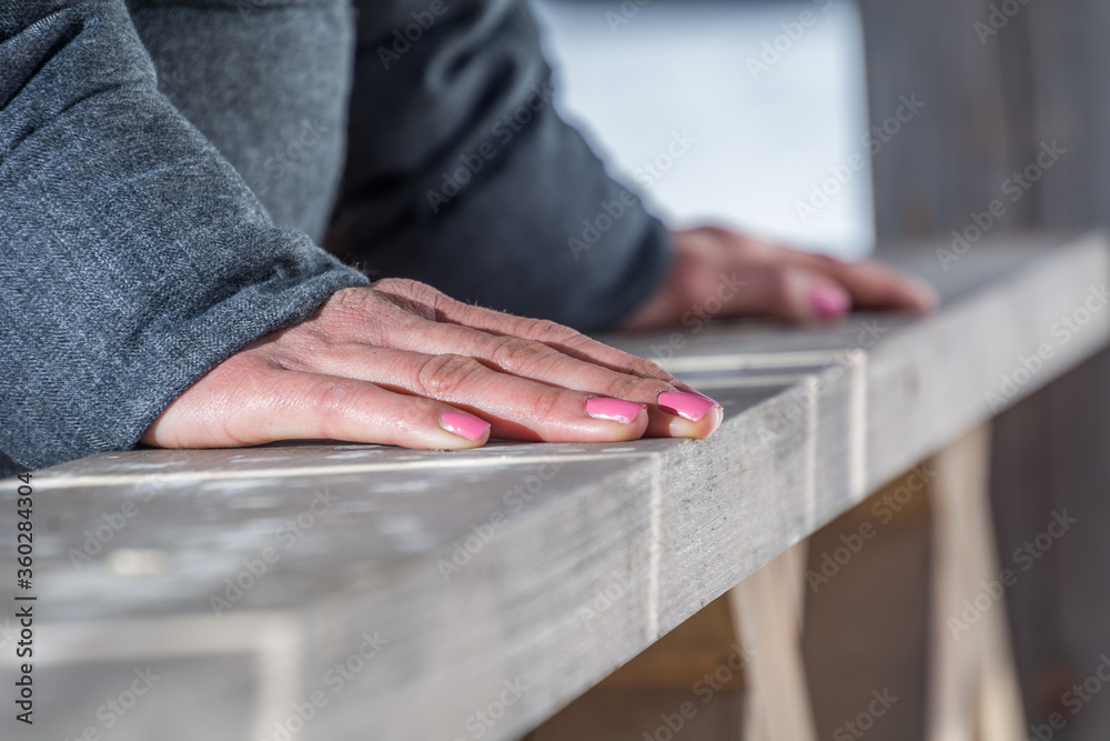 Young woman leaning against wooden fence wearing warm jacket. Close up view of hands palms. Nails painted in pink color. Winter season. Shallow depth of field Young woman leaning against wooden fence wearing warm jacket. Close up view of hands palms. Nails painted in pink color. Winter season. Shallow depth of field