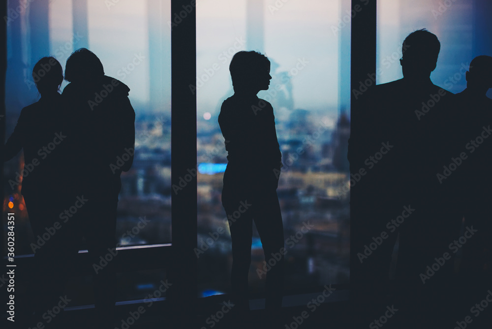 Silhouette of a young men and women office worker talking among themselves while they standing in office interior, successful partners discuss ideas during work break, confident colleagues at meeting