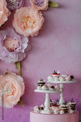 Catering sweets at the pink background with flowers with the place for your text. Dessert. Dessert table