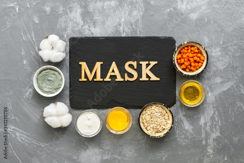 Natural ingredients for homemade cosmetic masks on a gray concrete background. Slate and wooden inscription mask. Top view, flat lay.