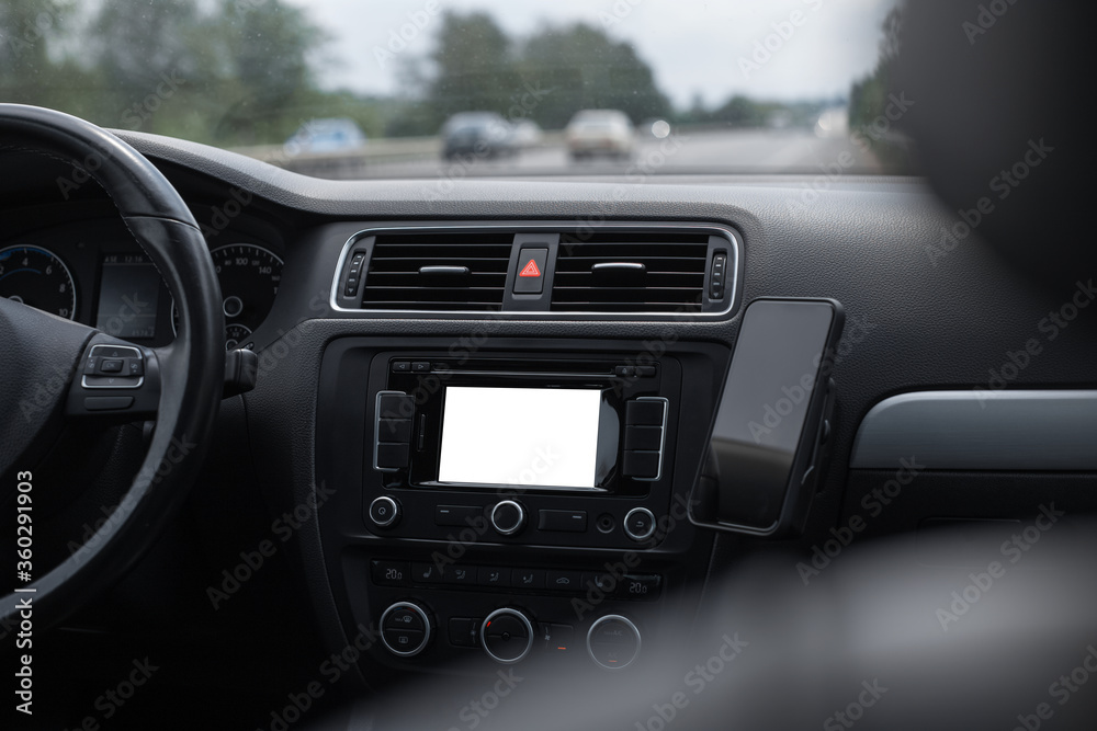Close-up view inside car of dashboard with empty mockup on screen, and smartphone. GPS navigation system concept.