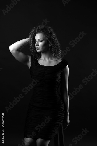 Black and white portrait of a cute curly girl in a black dress