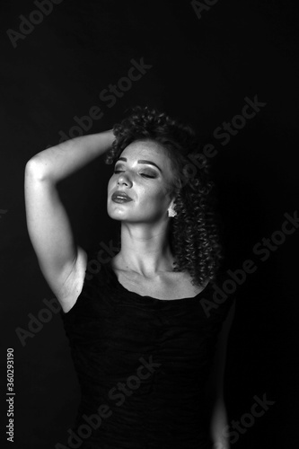 Black and white portrait of a cute curly girl in a black dress