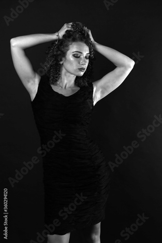 Black and white portrait of a cute curly girl in a black dress