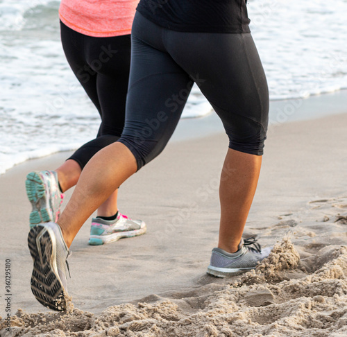 Two female runners on a beach by the water