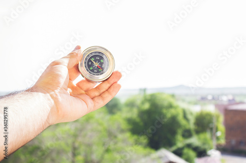 Holds compass against the background of nature