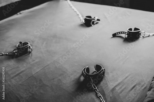 BDSM Leather handcuffs for role-playing games on a gray sheet. Bondage for carnal pleasures. Domination and submission.