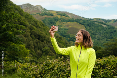 Young woman taking a selfie with her mobile phone after a hike in Asturias