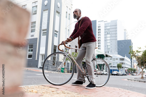 Fototapeta Naklejka Na Ścianę i Meble -  African American man sitting on his bike in the city street