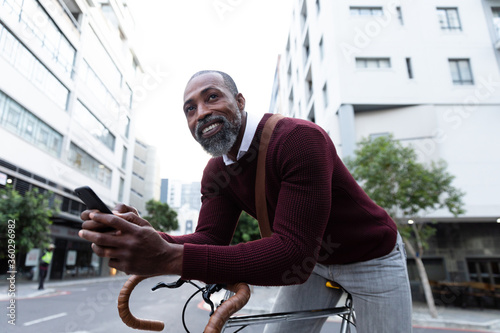 African American man sitting on his bike and using his phone 