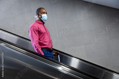 African American wearing covid19 coronavirus mask standing on escalator © wavebreak3