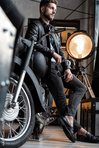 Stylish young man in leather jacket sitting on motorbike. © opolja