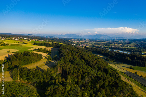 summer landscape with meadows, forest, fields and alpine panorama