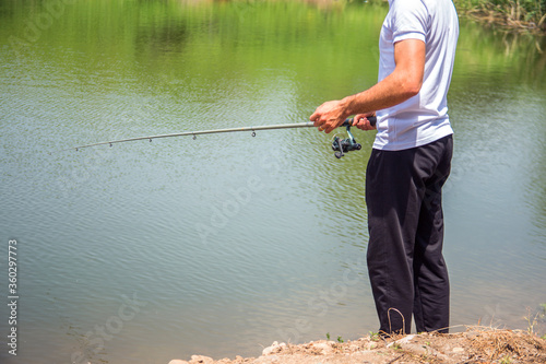 Fisherman on the river bank. Man fisherman catches a fish. Fisherman in his hand holding spinning