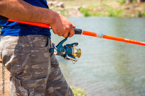 Fisherman on the river bank. Man fisherman catches a fish. Fisherman in his hand holding spinning