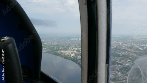 The view from the window of the porthole of a small passenger plane. Top view of the metropolis is a large green river on the banks Dnipro of which houses and briges are built. photo