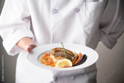 chef serving luxury seabass plate with hand photo