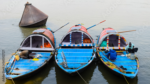 Photos INDIA, KOLKATA, 9th FEBRUARY 2020: Three boats are anchored on bank of river ganga have a solar panel for lighting and unrecognisable fishermen preparing breakfast on it