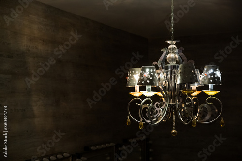 Close-up of antique chandelier with big yellow lightbulbs.Round big vintage lamp on black background.luxury big chandelier with many lamps and crystals.Copy space