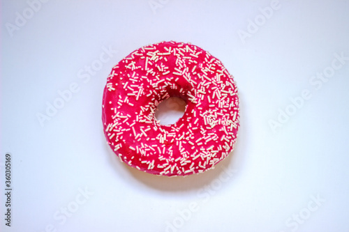 Pink frosted donut with colorful sprinkles isolated on white background. Sprinkled pink donut. Delicious food. Close up.