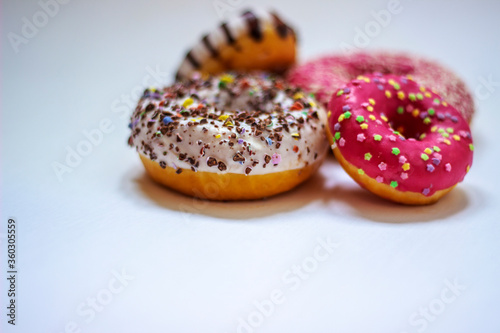Group of delicious colorful donuts of white background. Chocolate, pink and white glaze. Side view of round sweet dessert. Close up. Selective focus.