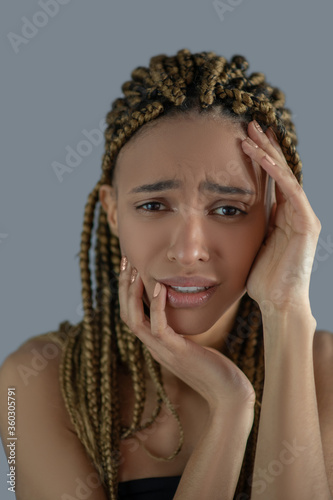 Devastated young African American holding her face with her hands  frowning with pain