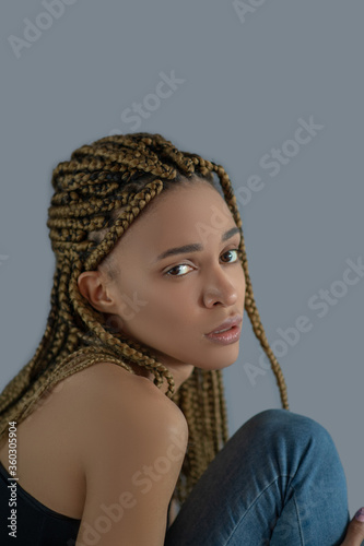 Disappointed young African American woman sitting, holding her knee
