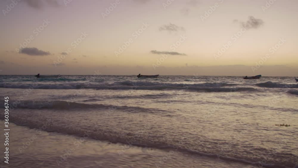 A sunrise with some boats floating over the waves in the coast of Tulum, Mexico. A sunrise with some boats floating over the waves in the coast of Tulum, Mexico.