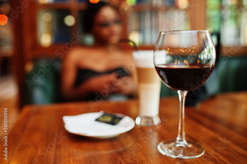 Close up glasses of wine against african american woman at restaurant.