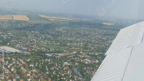 The view from the window of the porthole of a small passenger plane against a white wing. Top view of the metropolis. Small houses and cars. photo