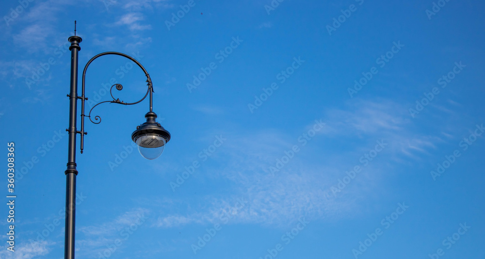 A lone street lamp post is isolated in the blue sky. summer concept. A lone street lamp post is isolated in the blue sky. summer concept.