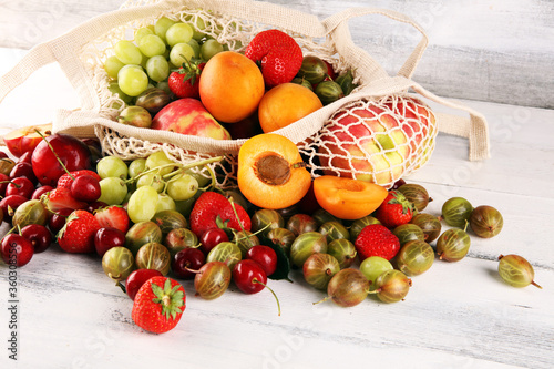 Fototapeta Naklejka Na Ścianę i Meble -  Fresh summer fruits in eco bag with apple, grapes, berries, plums and healthy apricot.