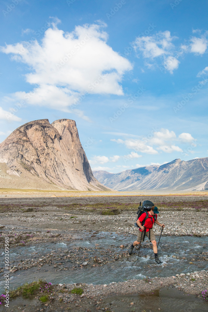 Hiker crosses river in Akshayak Pass. Hiker crosses river in Akshayak Pass.