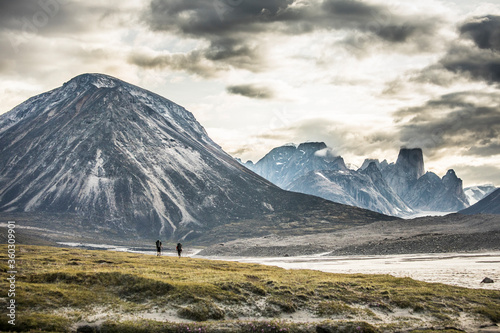 Silhouette of two backpackers hiking through dramatic mountain pass. photo