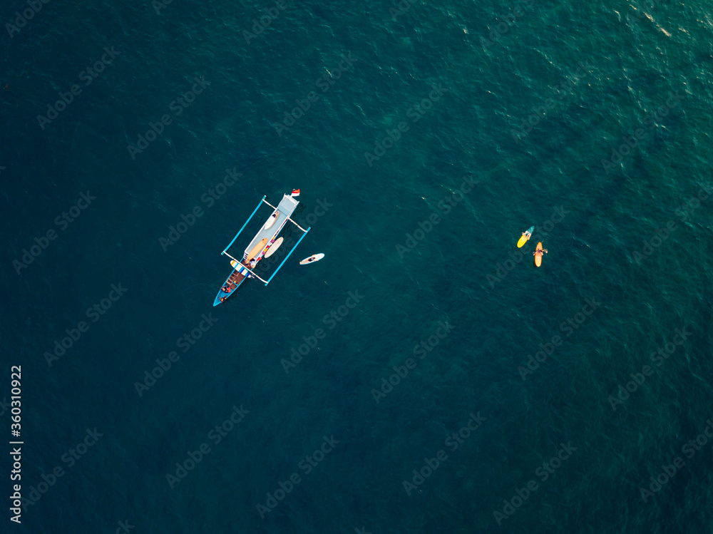 Aerial view of surfers and boat in the ocean, Lombok, Indonesia Aerial view of surfers and boat in the ocean, Lombok, Indonesia