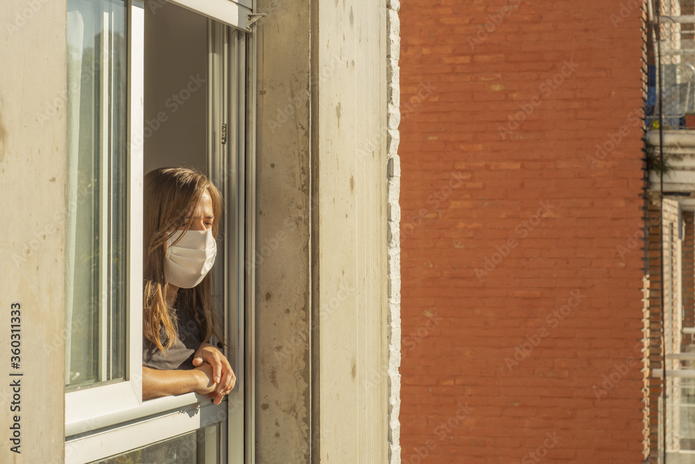 Woman in the windows during quarantine using a mask Woman in the windows during quarantine using a mask