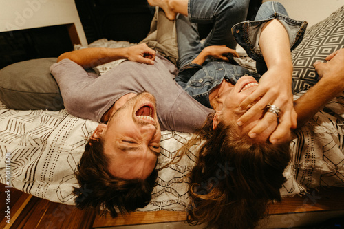 engaged couple relax and laugh lying upside down on their van bed photo