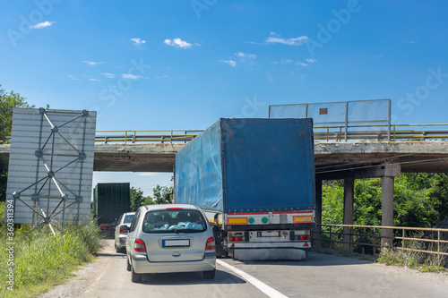 Blue track trying to pass under the elevated road. Truck colliding with bridge