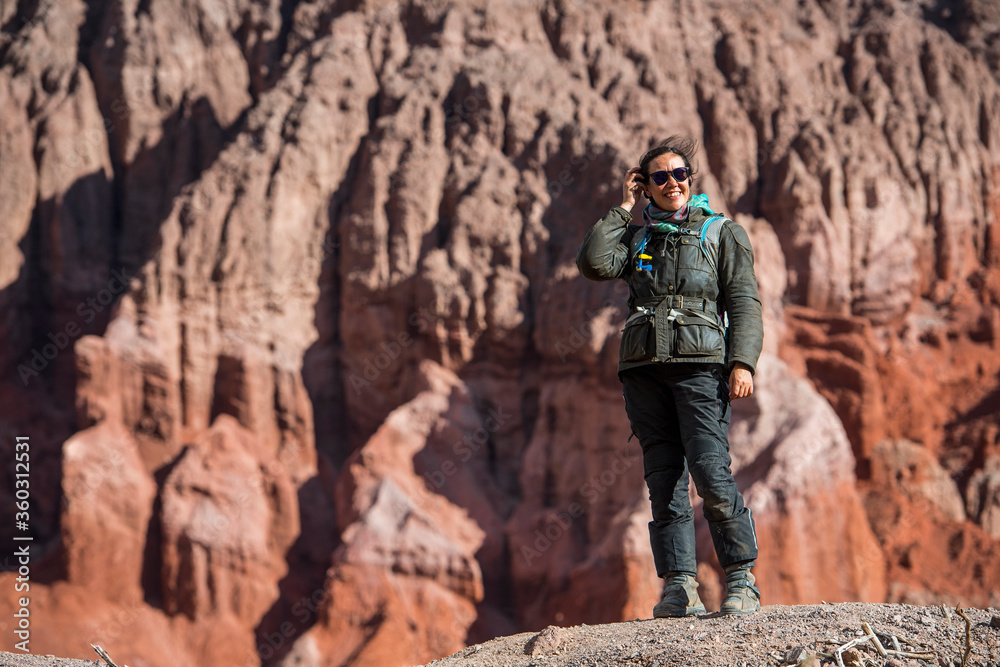 Woman in motorcycle gear, standing in front of red sandstone formation Woman in motorcycle gear, standing in front of red sandstone formation