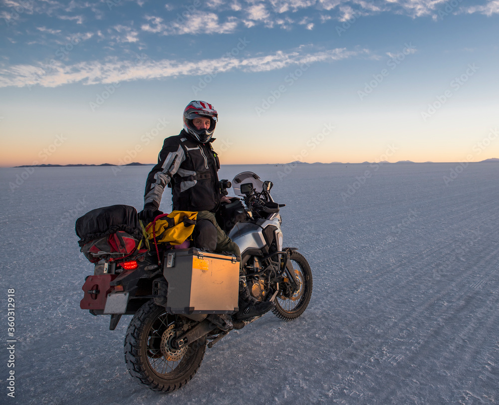 Man riding his touring motorbike on the salt flats of Uyuni in Bolivia Man riding his touring motorbike on the salt flats of Uyuni in Bolivia
