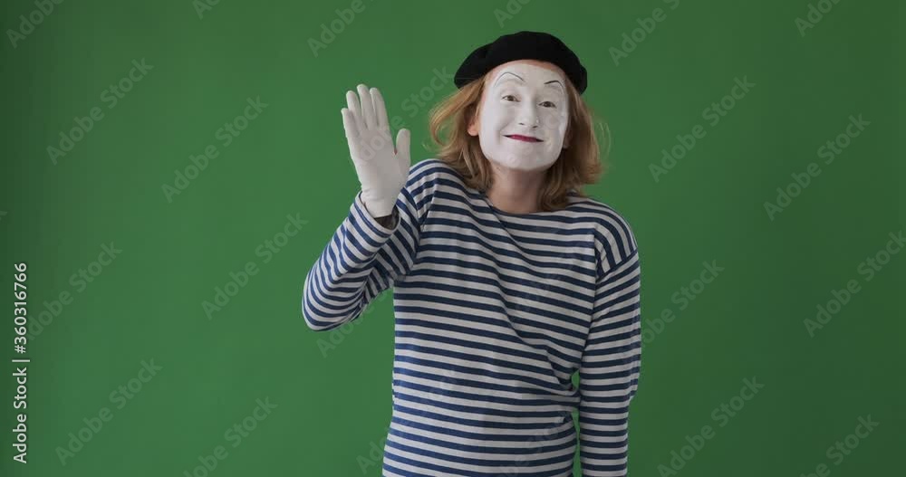 Happy male mime artist waving hand and greeting over green background Happy male mime artist waving hand and greeting over green background