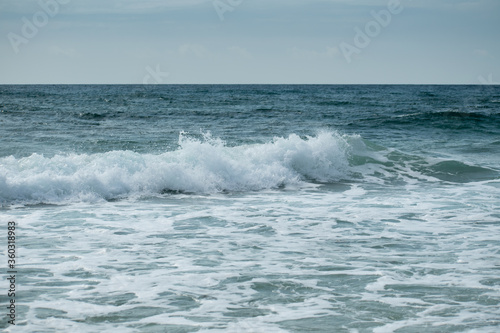 Small cresting wave in the Atlantic Ocean on the coast. Blue green ocean waves with sea foam and salt water spray. Beach travel photos. © SohanKhalsaCreative