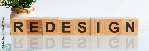 REDESIGN word concept written on wooden blocks, cubes on a white table with a flower and a light background photo