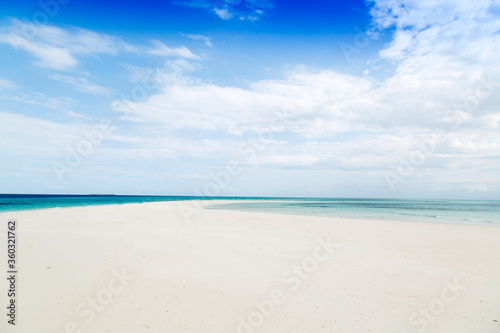 Clean white sand beach with turquoise water . Tropical island background. Small waves crushing on the beach. Clean empty white sand beach on Zanzibar. Isolated on the tropical beach 