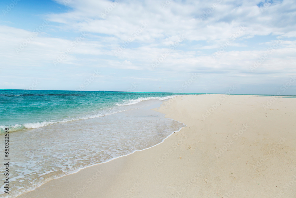 Clean white sand beach with turquoise water . Tropical island background. Small waves crushing on the beach. Incoming tide Clean white sand beach with turquoise water . Tropical island background. Small waves crushing on the beach. Incoming tide