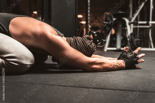 A sporty man in the gym is doing Yoga exercises. Back stretch exercise. Yoga position - Sasangasana. Yoga mental benefits.