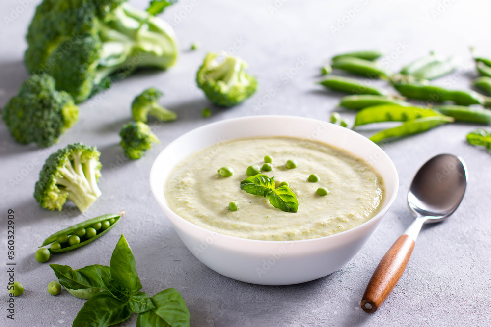 Bowl of broccoli and green peas cream soup on a concrete background Bowl of broccoli and green peas cream soup on a concrete background