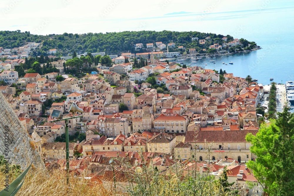 Hvar, Croatian island. High angle, panorama view of the old town, partial view of the sea. Terracotta coloured rooftops. 